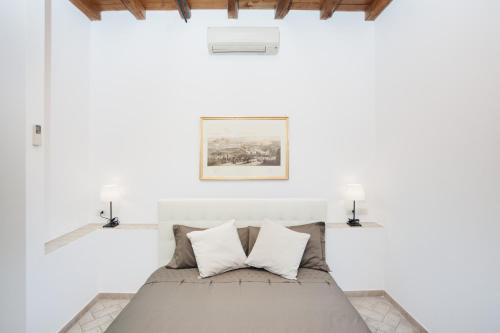 a white bedroom with a bed with two pillows at Tritone 91 Apartments in Rome