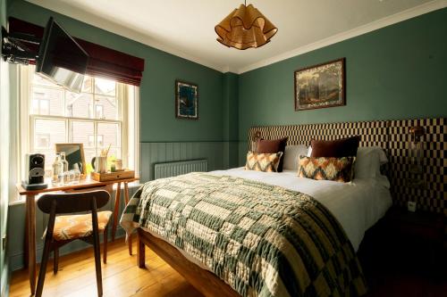 a bedroom with green walls and a bed and a desk at The Swan in Arundel