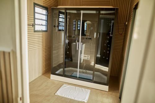 a walk in shower with a glass door in a room at Echoes of forest in Andasibe
