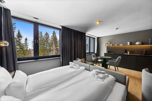 a bedroom with a large bed and a living room at TRIFORET alpin resort by Falkensteiner in Hinterstoder
