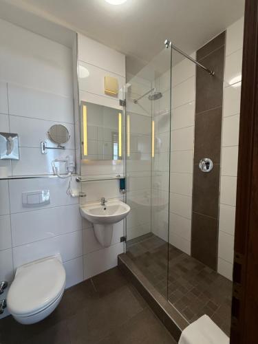 a bathroom with a toilet and a sink and a shower at Shin Central Self-Check-in in Essen