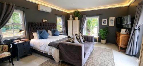 a bedroom with a bed and a chair and windows at Sandmartins Private Secure Villa in Simondium