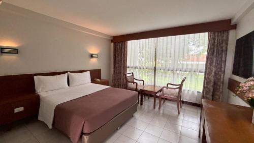 a hotel room with a bed and a table and a window at โรงแรมฉัตรแก้ว in Ban Dan Chang