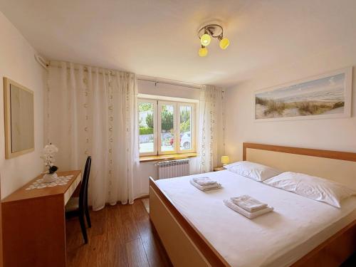 a bedroom with a bed and a desk and a window at Apartments Nevenka K. in Čižići