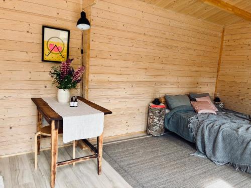 a room with a bed and a table in a wooden wall at Haapsi Hideaway Garden Cabin in Haapsi