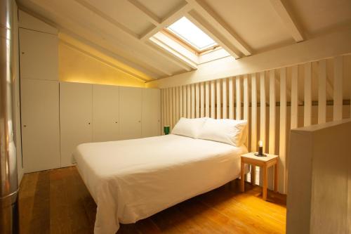 a bedroom with a white bed and a skylight at Estúdio 24 na Boavista, JAMBA House in Porto