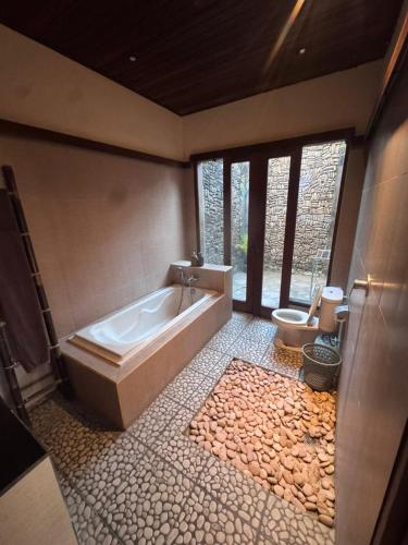 a large bathroom with a tub and a toilet at Intan Villa & Suite Ubud in Ubud