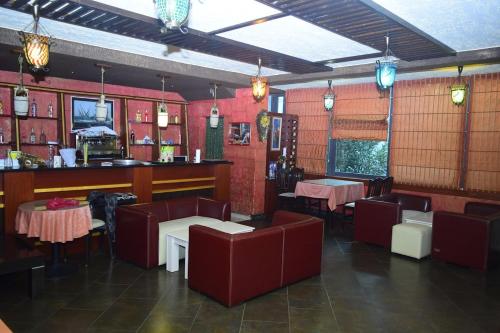 ein Restaurant mit roten Wänden, Tischen und Stühlen in der Unterkunft Hotel Deja in Tirana