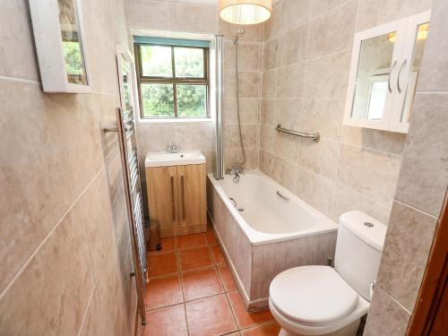 a bathroom with a toilet and a tub and a sink at Swallow Cottage in Helston