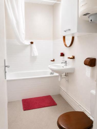 a bathroom with a white tub and a sink and a red rug at Studio - Pleine Mer - 1 avenue des Pays de Monts - 1-1 in Saint-Jean-de-Monts