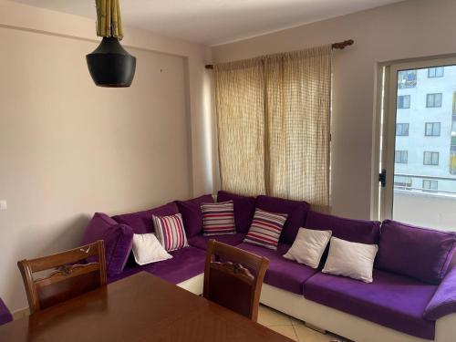 a purple couch in a living room with a window at Olive in Tirana