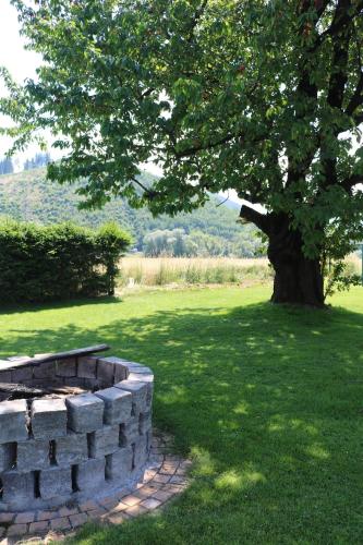 a stone wall next to a tree in a field at Lenz Stay - Ganzes Ferienhaus mit privatem Garten in Kaisersberg