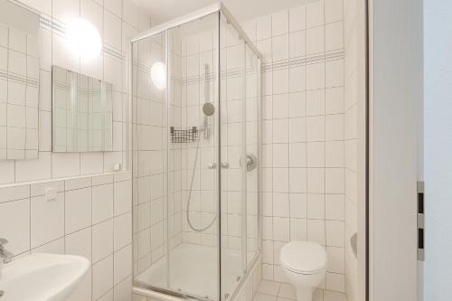 a white bathroom with a shower and a toilet at City Lodge Leipzig in Leipzig