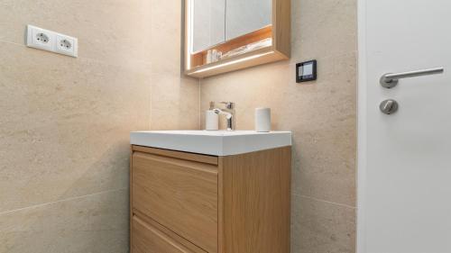 a bathroom with a white sink and a wooden cabinet at Villa Aquiterra Bobovisca in Bobovišća