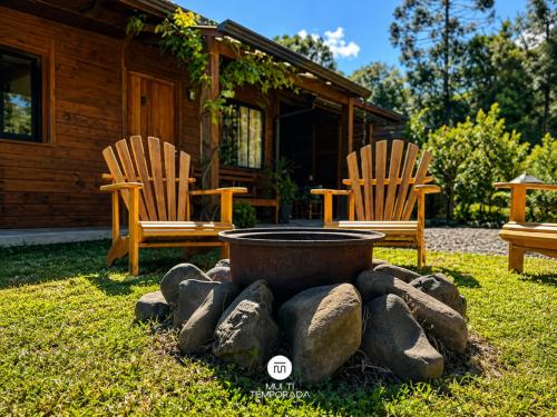 two chairs and a fire pit in front of a cabin at Casa Completa | 2 Suítes + Jardim com Fogo de Chão in Urubici