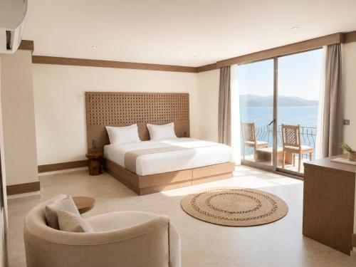 a bedroom with a bed and a chair and a balcony at Villa Hotel Tamara in Kaş