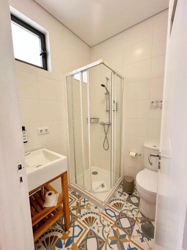 a bathroom with a shower and a sink and a toilet at Boavista Guest House in Porto