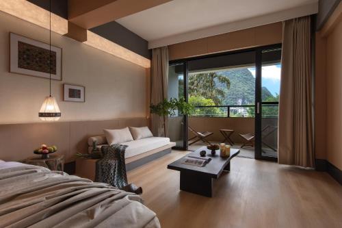 a bedroom with a bed and a couch and a table at L'Eau Vive de Qixi Meidi - Riverfront Infinity Pool & Log Cabin Cafe - Outdoor Cooking Class - Complimentary Shuttle within 8 Kilometers in Yangshuo