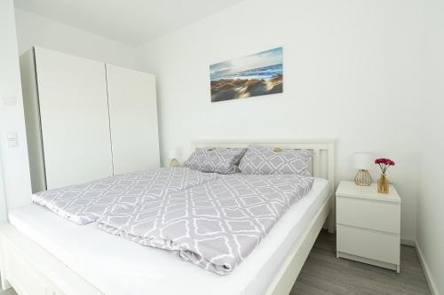 a white bedroom with a bed and a white cabinet at Sonne & Sand Strandnahes Ferienhaus mit Whirlpool, Sauna & Wallbox in Büsum