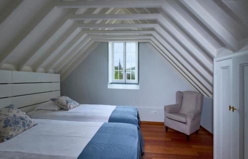 a bedroom with two beds and a chair at Casa Dos Barcos Furnas in Furnas
