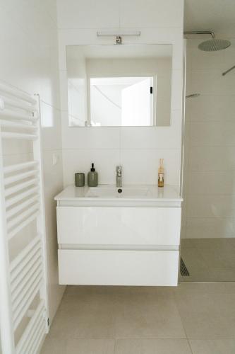 a white bathroom with a sink and a mirror at Oase in Bergen