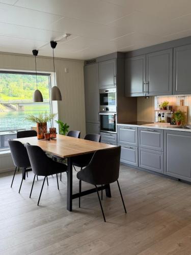 a kitchen with a wooden dining table and chairs at Modern lakefront apt with view - EV plug in Stryn