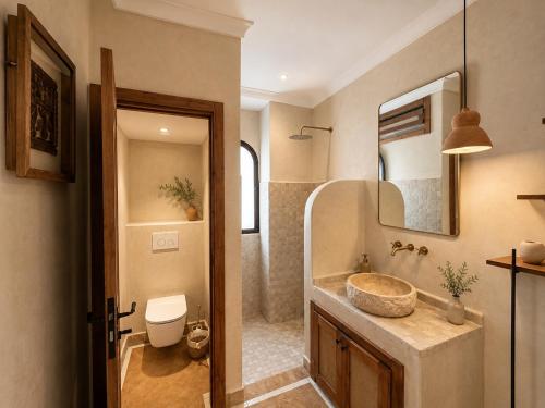 a bathroom with a sink and a toilet and a mirror at Riad Timoun in Agadir