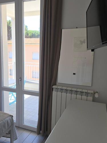 a room with a large window and a door at camera con terrazza vicino al mare e pineta in Follonica