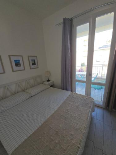 a bedroom with a bed and a sliding glass door at camera con terrazza vicino al mare e pineta in Follonica