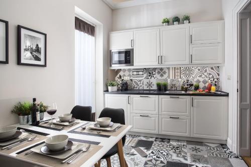 een keuken met witte kasten en een tafel en stoelen bij Brill Budapest Apartments 3 in Boedapest