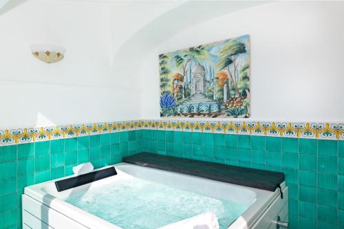 a bath tub in a bathroom with a painting on the wall at Hotel L'Ancora in Positano