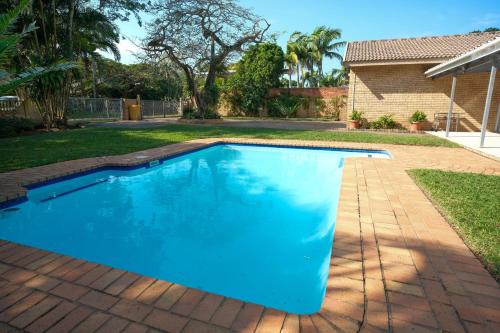 a blue swimming pool in a yard with a house at Kuda Breeze in St Lucia