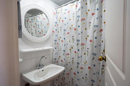 a bathroom with a sink and a shower curtain with flowers at Hotel Asimina Laganas in Laganas