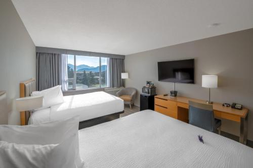 a hotel room with two beds and a desk and a television at Coast Chilliwack Hotel by APA in Chilliwack