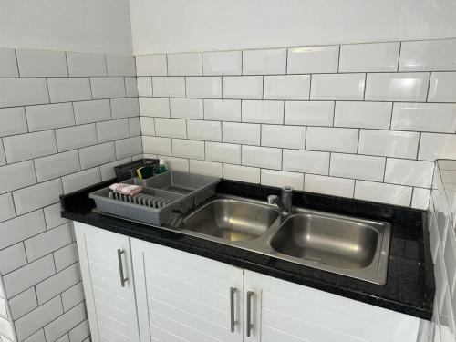 a kitchen with a stainless steel sink and white tiles at #9 Illovo Views in Kingsborough