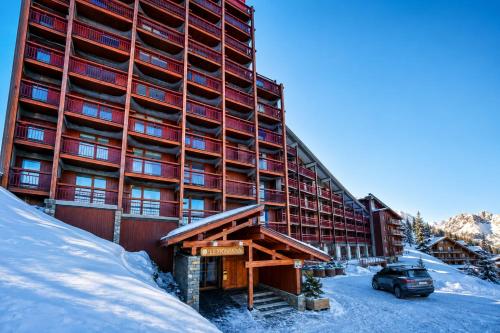 a large building with a car parked in the snow at Résidence LE VARET - ARC 2000 - Ski-in Ski-out in Bourg-Saint-Maurice
