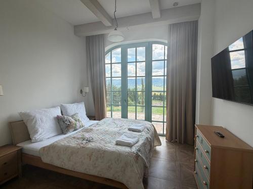 a bedroom with a bed and a large window at Farma HUGÁNIKOVO - families, pets & spa relaxation in Brezno
