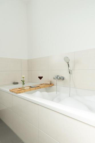 a white bath tub with a glass of wine at Sonne & Sand Strandnahes Ferienhaus mit Whirlpool, Sauna & Wallbox in Büsum