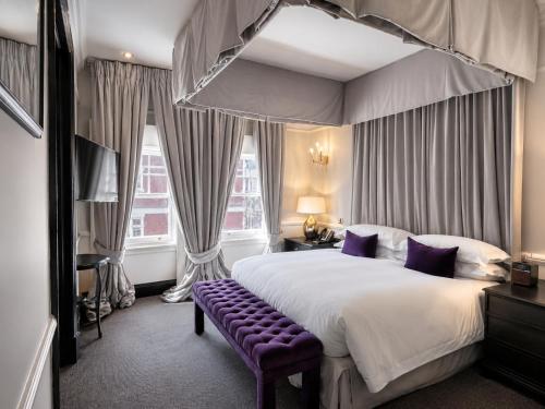 a bedroom with a large bed and a purple bench at 11 Cadogan Gardens and The Apartments in London