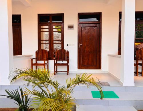 a house with a wooden door and two chairs at Blue Wings Arugam Bay in Arugam Bay