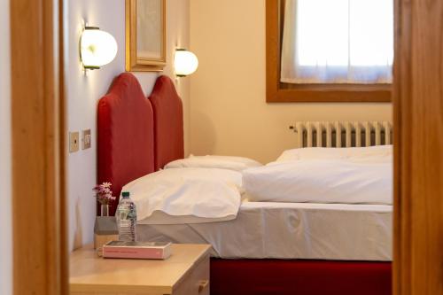 a bedroom with two beds and a table with a bottle of water at Bormiohomes - Case SteLu in Bormio