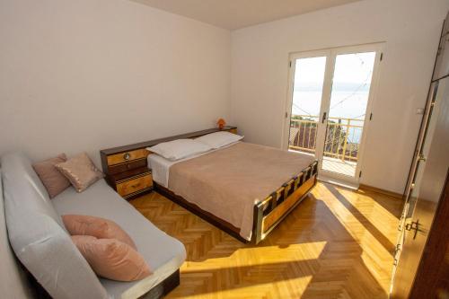 a bedroom with a bed and a couch and a window at Apartmani Jasna in Omiš