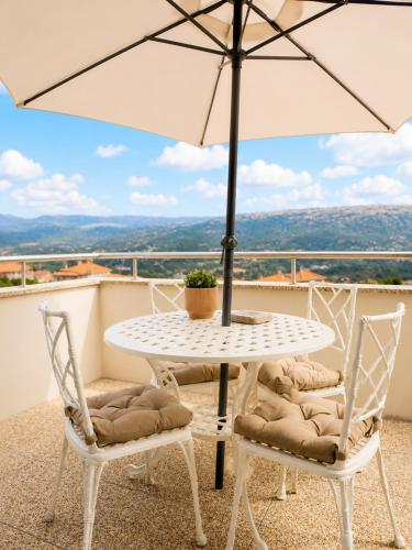 a white table and chairs with an umbrella on a balcony at Casa do Alto Vila Caiz in Amarante