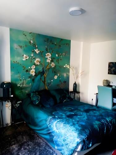 a bedroom with a blue bed with a painting on the wall at Villa Stella in Montauban