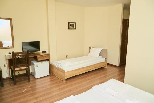 ein Zimmer mit einem Bett, einem Schreibtisch und einem Fernseher in der Unterkunft Family Hotel Fedora in Ribarica