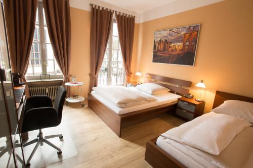 ein Schlafzimmer mit zwei Betten und einem Schreibtisch und einem Stuhl in der Unterkunft Stadthotel Jülich in Jülich