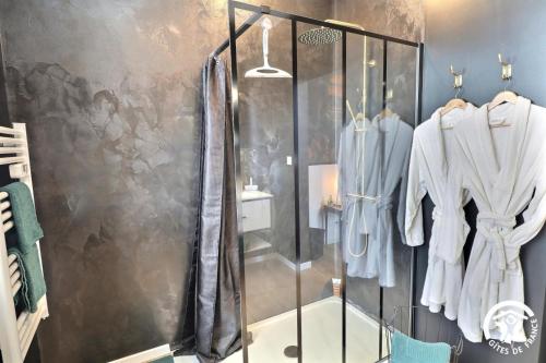 a shower in a bathroom with clothes on racks at Le rok in Billé