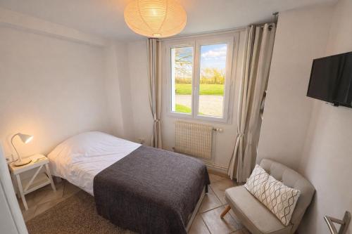 a bedroom with a bed and a window and a chair at Les Henrions in Pierrelatte