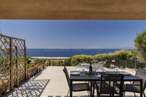 a table and chairs on a patio with a view of the ocean at Villetta Luce Marina in Costa Paradiso
