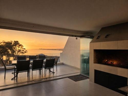 a dining room with a fireplace and a table and chairs at '24 Gordonia', Spacious Condo - Sleeps 7, Sea Front, Easy Beach access in Gordonʼs Bay
